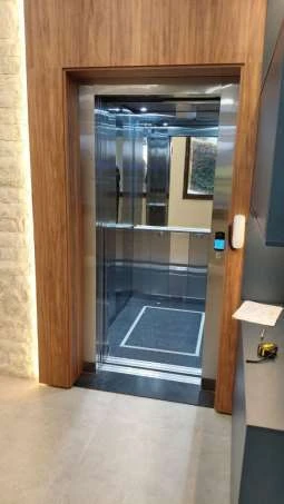 Elevador instalado em hall com acabamento em madeira